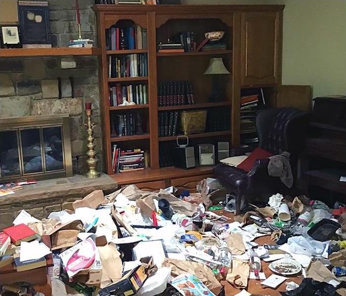 A living room is strewn with clutter and garbage.