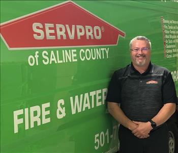 male employee standing in front of a SERVPRO green truck.