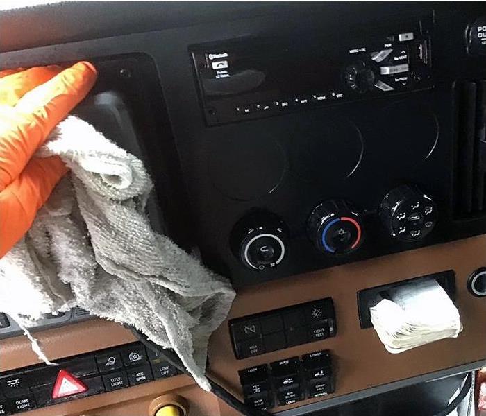 Glove-covered hand cleans and sanitizes big rig panel
