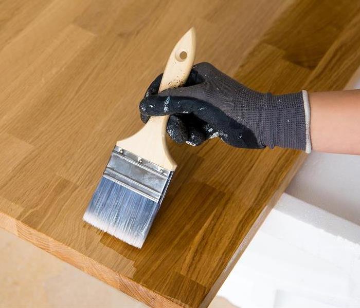 Linseed oil is brushed onto a butcher block countertop is brushed with a paint brush.