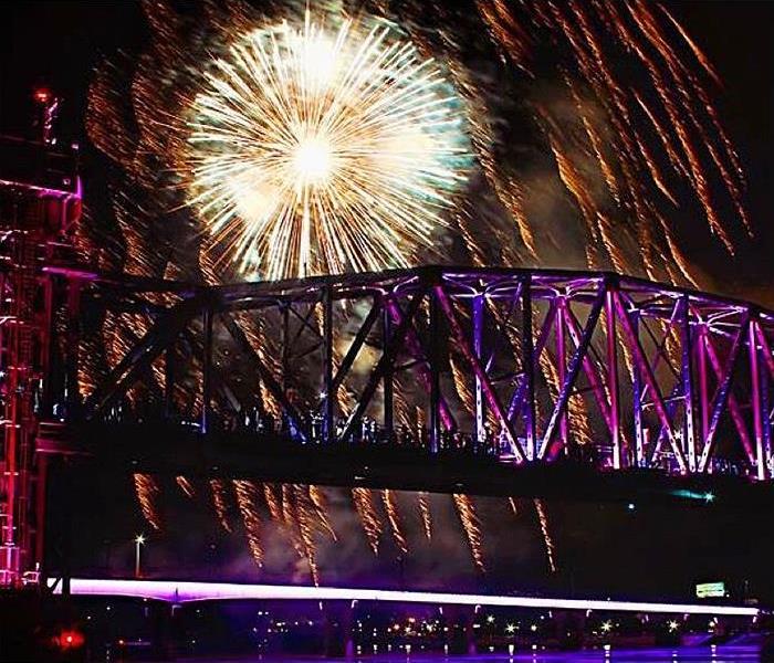 Fireworks explode over a bridge at night