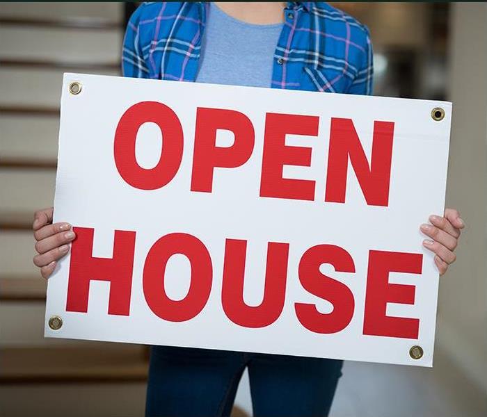 Woman holding an OPEN HOUSE sign