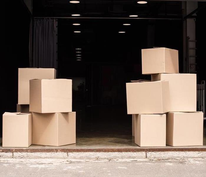 Packed boxes sit on the floor of an open warehouse door