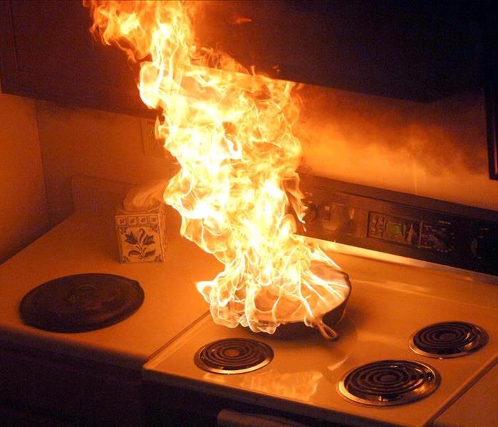 Flames shoot from a burning pan on a stove